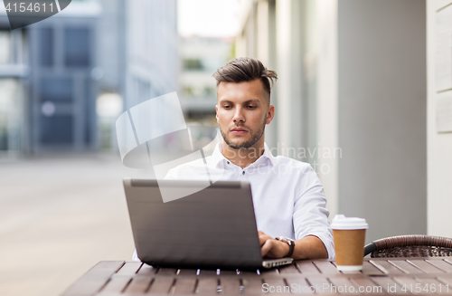 Image of man with laptop and coffee at city cafe