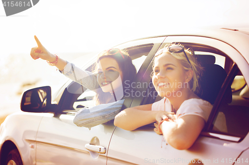 Image of happy teenage girls or women in car at seaside