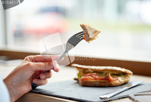 Image of woman eating salmon panini sandwich at restaurant