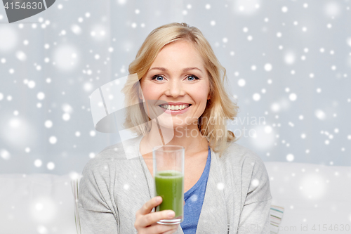 Image of happy woman drinking green juice or shake at home