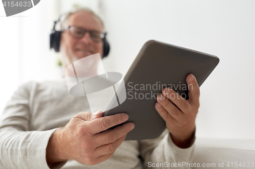 Image of senior man with tablet pc and headphones at home