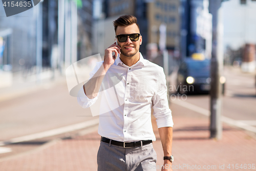 Image of happy man with smartphone calling on city street