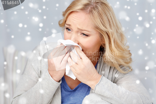 Image of ill woman blowing nose to paper napkin