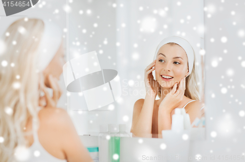 Image of woman in hairband touching her face at bathroom