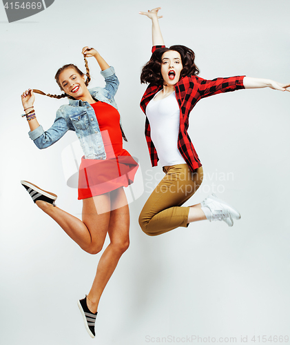 Image of two pretty brunette and blonde teenage girl friends jumping happy smiling on white background, lifestyle people concept