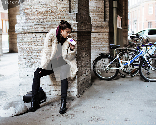 Image of young pretty stylish teenage girl outside at city wall with graf