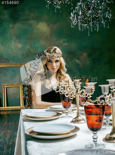 Image of young blond woman wearing crown in fairy luxury interior with em