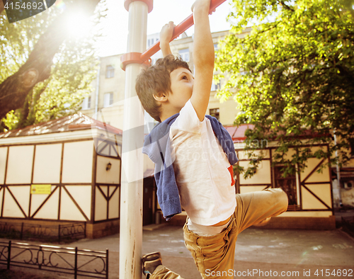 Image of little cute blond boy hanging on playground outside, alone training with fun, lifestyle children concept