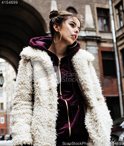 Image of young pretty stylish teenage girl outside at city wall with graf