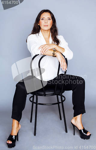 Image of pretty brunette confident mature woman sitting on chair in studi