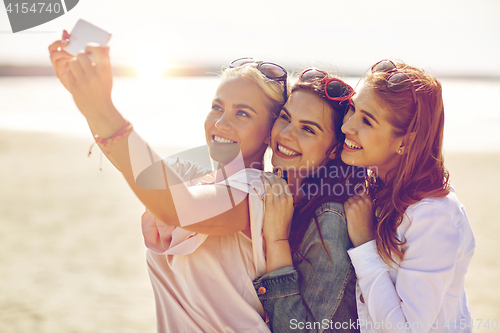 Image of group of smiling women taking selfie on beach
