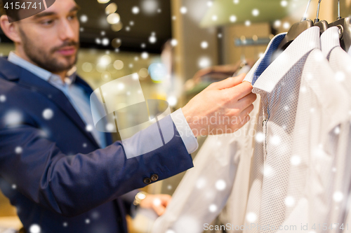 Image of close up of man choosing shirt in clothing store