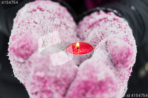 Image of close up of hands in winter mittens holding candle