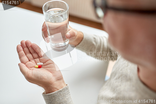 Image of close up of old man hands with pills and water