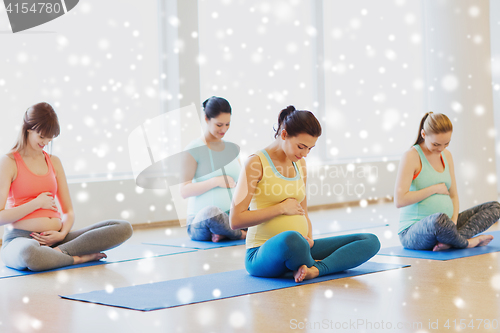 Image of happy pregnant women exercising yoga in gym