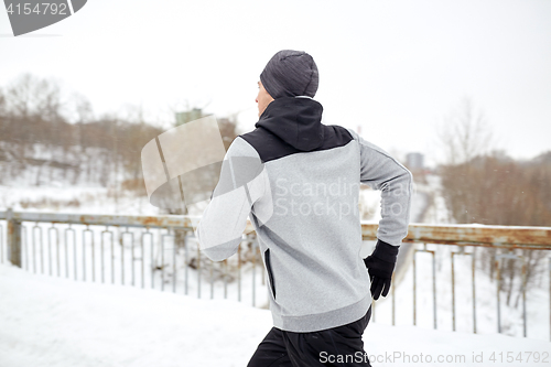 Image of man running along snow covered winter bridge road