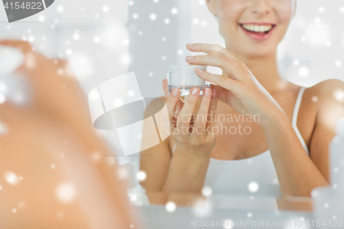 Image of happy woman with face cream at bathroom