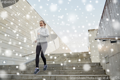 Image of happy sporty woman running downstairs in city