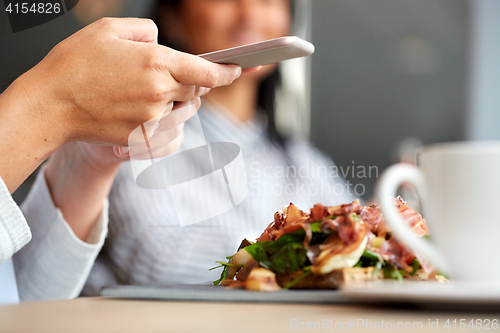 Image of woman with smartphone and ham salad at restaurant