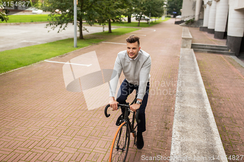 Image of young man riding bicycle on city street