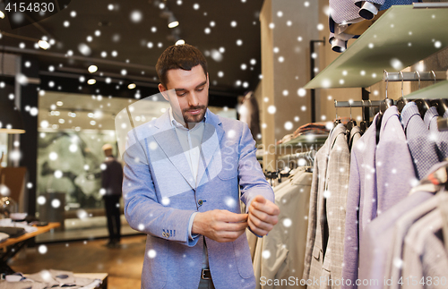 Image of happy young man trying jacket on in clothing store
