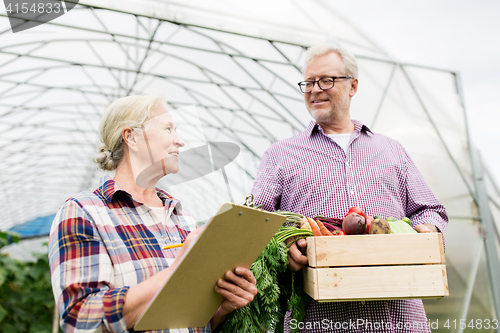 Image of senior couple with box of vegetables on farm