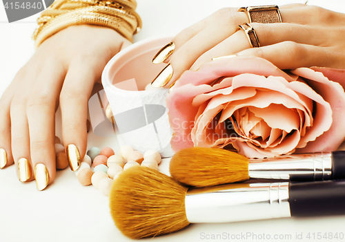 Image of woman hands with golden manicure and many rings holding brushes,