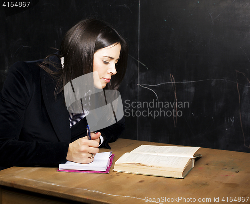 Image of portrait of happy cute student in classroom at blackboard back t