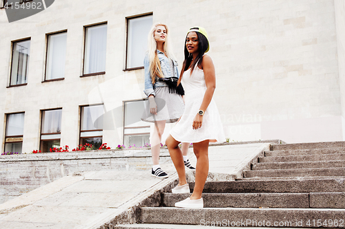 Image of Two teenage girls infront of university building smiling, having