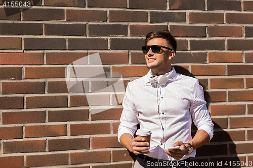 Image of man with smartphone and coffee cup on city street