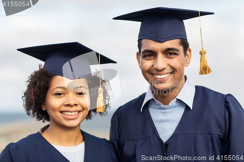 Image of happy students or bachelors in mortar boards