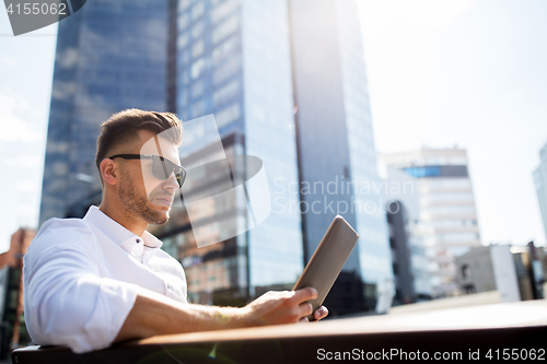 Image of man with tablet pc sitting on city street bench