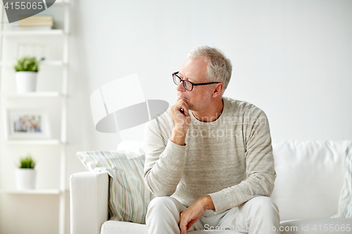 Image of  senior man sitting on sofa at home and thinking