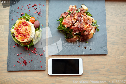 Image of goat cheese and ham salads with smartphone at cafe