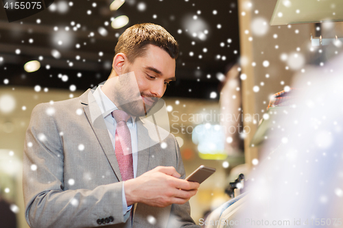 Image of man in suit with smartphone at clothing store