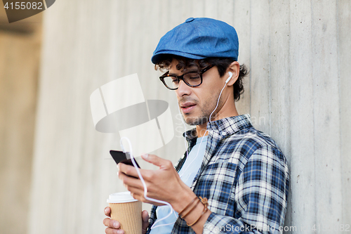 Image of man with earphones and smartphone drinking coffee