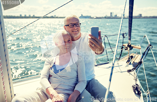 Image of seniors with smartphone taking selfie on yacht