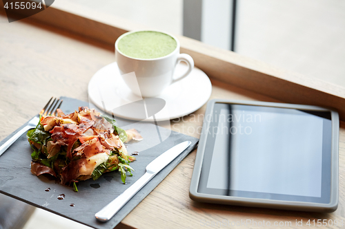 Image of prosciutto ham salad with tablet pc at restaurant