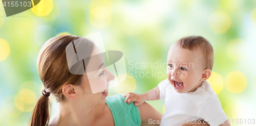 Image of happy mother with little baby over green lights