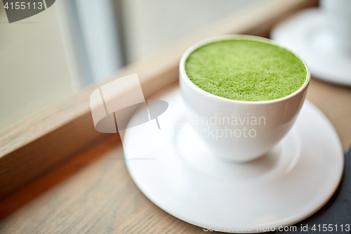 Image of white cup of matcha green tea latte on table