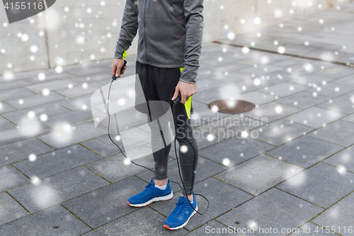 Image of close up of man exercising with jump-rope outdoors