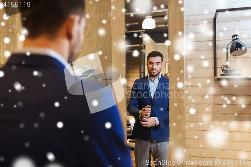 Image of man trying jacket on at mirror in clothing store