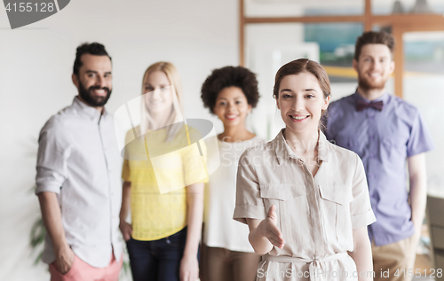 Image of woman making handshake over creative office team