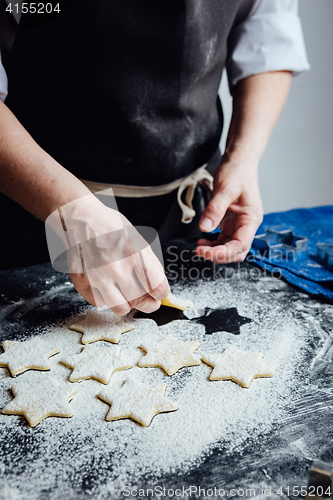 Image of Person putting raw cookies to flour