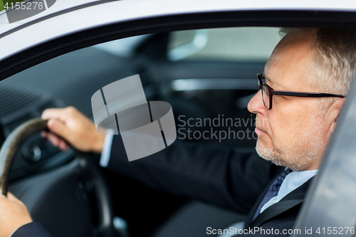 Image of happy senior businessman driving car