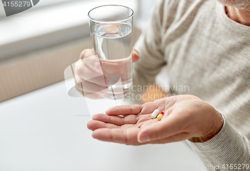 Image of close up of old man hands with pills and water