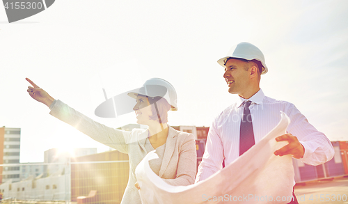 Image of happy architects with blueprint at building