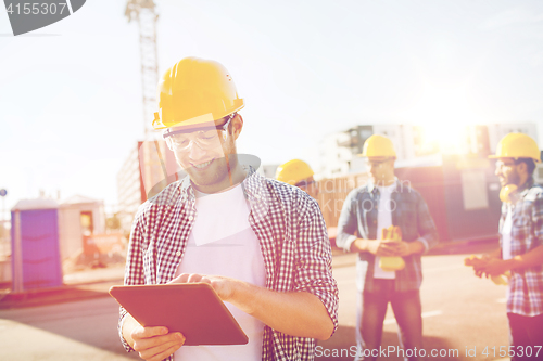 Image of smiling builders in hardhats with tablet pc