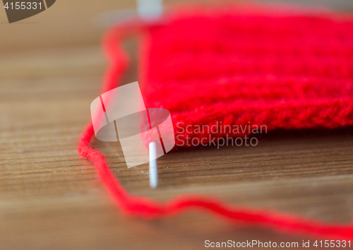 Image of hand-knitted item with knitting needles on wood