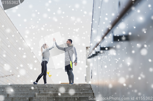 Image of couple of sportsmen making high five outdoors